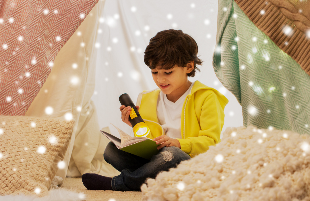 Child reading a book with a flashlight inside a cozy tent